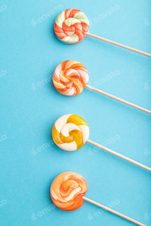 Preview: Four lollipop candies on blue background. copy space, top view