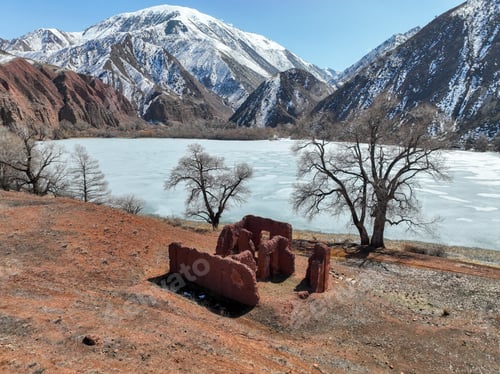 Preview: Ancient ruins on red earth overlooking a frozen mountain lake