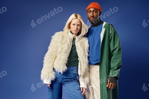 Preview: attractive woman in white faux fur jacket near african american man on blue, interracial couple