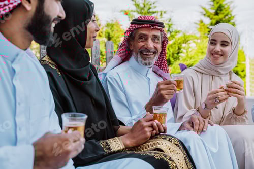 Preview: Middle eastern muslim family enjoying tea and togetherness outdoors