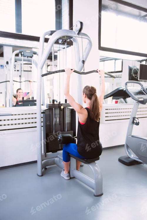 Preview: Young woman doing exercises on a machine at the gym