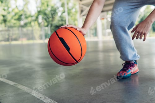 Preview: Hand of a boy bouncing a basketball on a court