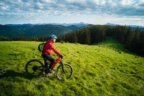 Preview: Cyclist man riding electric bike outdoors, enjoying beautiful mountain landscape.