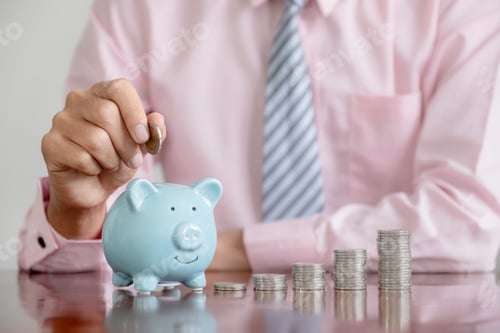 Preview: Businessman hand putting coin into blue piggy bank