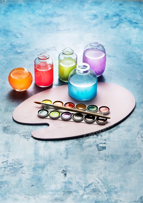Preview: Colorful watercolor paints in glass bottles and the artist's palette. Creative art background
