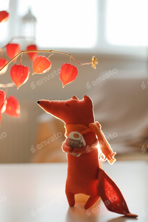 Preview: autumn still life with a toy fox, flowers, twigs of red physalis in a vase in a cozy home interior
