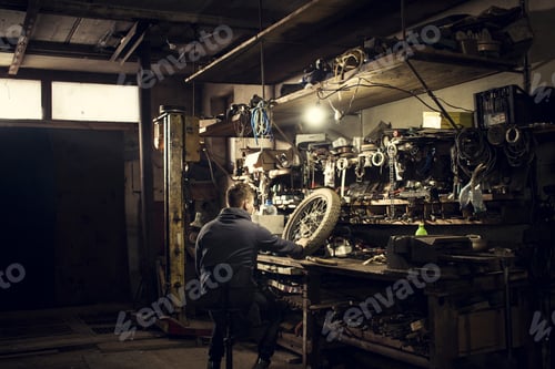 Preview: Mechanic repairing vintage motorcycle wheel at workshop bench