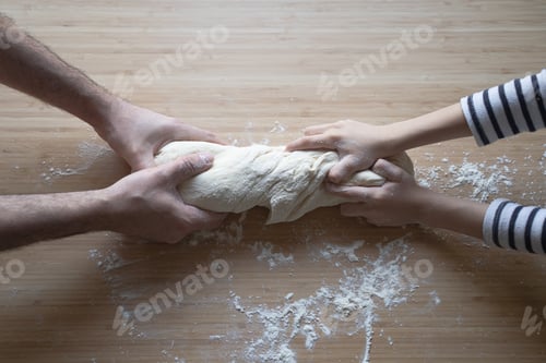 Preview: little Caucasian girl working the dough with her father on a wood cutting board