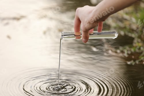 Preview: a specialist s hand draws water into a flask from a river for further research in the laboratory.