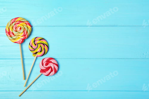 Preview: Tasty candies and space for text on color wooden background, top view