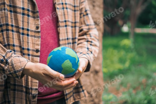 Preview: An Asian woman holds a globe in green forest,symbolizing importance preserving nature.emphasizes