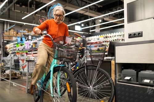 Preview: Woman shopping for home and garden supplies in a large retail store with a bicycle