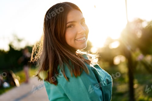 Preview: Portrait of young woman in green shirt smiling in a park