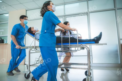 Preview: a group of medics or doctors carrying male patient on hospital gurney to emergency