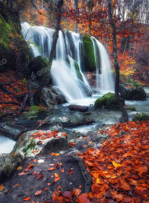 Preview: Waterfall at mountain river in autumn forest at sunset.
