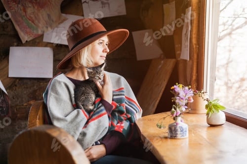 Preview: Woman in poncho and hat with small tabby kitten