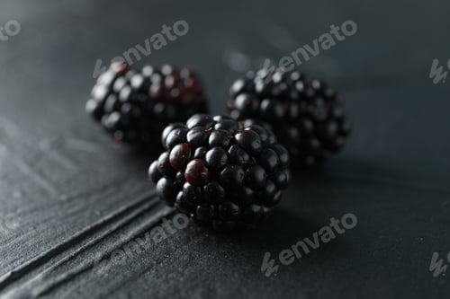 Preview: Blackberries on black cement background, closeup and space for text