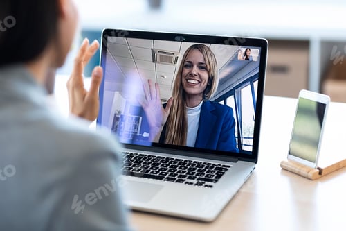 Preview: female employee waving and speaking on video call with her colleague on online briefing