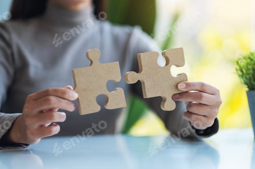 Preview: Closeup image of a woman holding and putting a piece of wooden jigsaw puzzle together