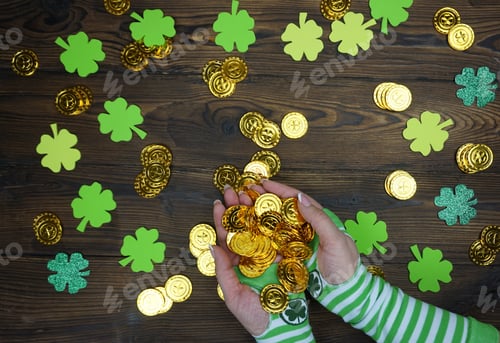 Preview: The girl's hands in striped gloves hold coins with a four-leaf clover