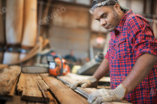 Preview: A reclaimed lumber workshop. A man measuring and checking planks of wood for re-use and recycling.