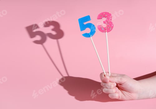 Preview: girl's hand holding a number five and three shaped lolipop. anniversary or birthday selebration
