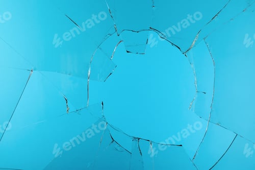 Preview: Closeup view of broken glass with cracks on light blue background