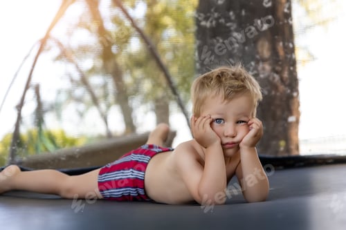 Preview: Portrait of cute bored little caucasian funny sad blond toddler boy lying inside big black