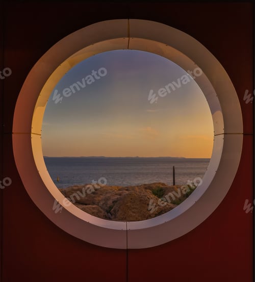 Preview: Round window from the inside of a room with the sea at sunset in the background