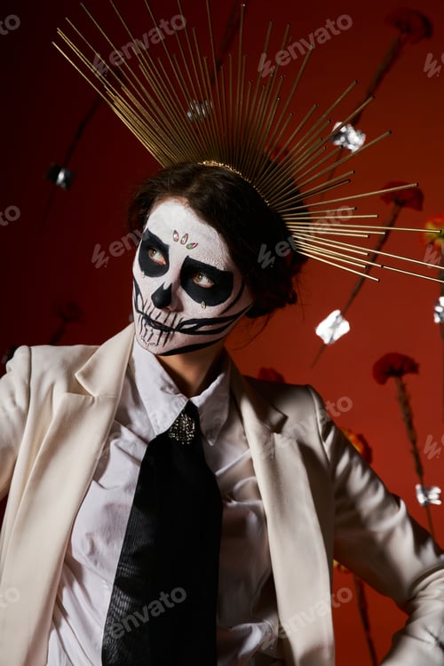 Preview: elegant woman in dia de los muertos catrina makeup and crown looking away on red floral backdrop
