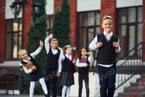 Preview: Group of kids in school uniform posing to the camera outdoors together near education building