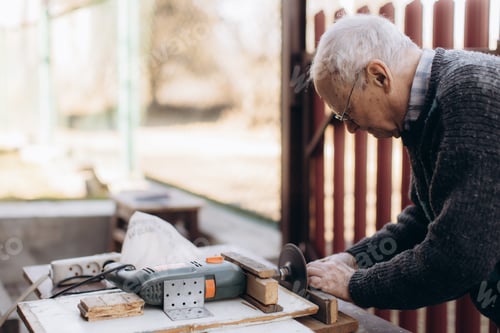 Preview: Elderly Man Working with a Grinder in a Workshop