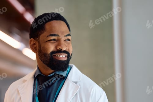 Preview: Happy black doctor at medical clinic looking away.