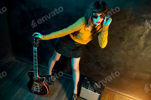 Preview: Young Woman Holding Guitar Against Dark Background