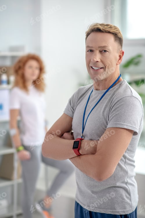 Preview: Male physiotherapist standing with folded arms, smiling
