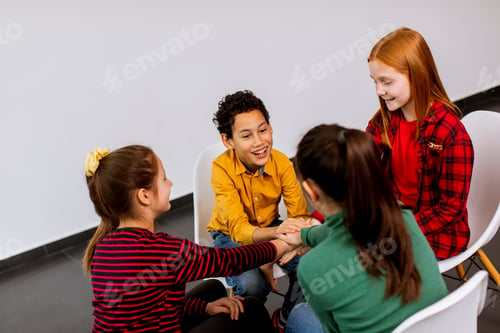 Preview: Portrait of cute little kids in jeans talking and sitting in chairs against white wall