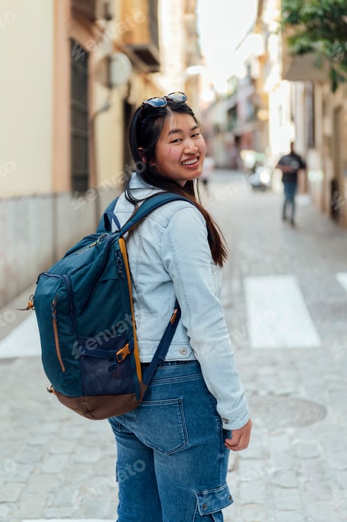 Preview: traveler woman looking back with backpack on the street