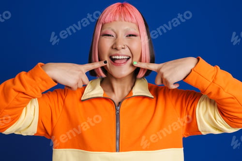 Preview: Asian girl with pink hair and piercing pointing fingers at her smile