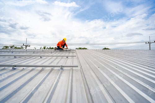Preview: Technician in safety uniform and helmet kneeling on a rooftop