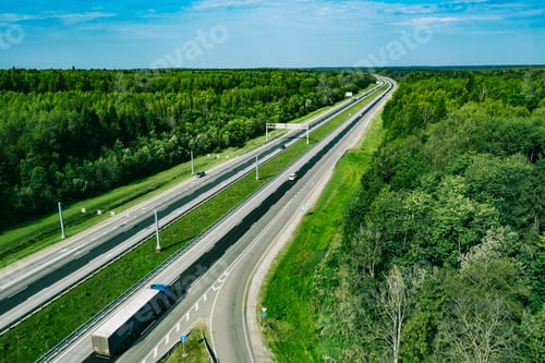 Preview: Aerial drone view of highway asphalt road with cars and trucks driving through green summer woods