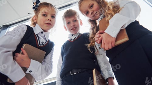 Preview: School kids in uniform posing for a camera together in corridor. Conception of education