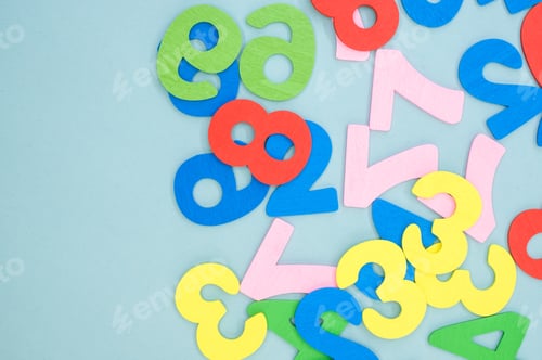 Preview: Flat lay of colorful wooden numbers on a blue surface - space for text