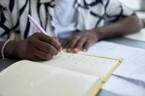 Preview: Focus on hand of young African American male student making notes