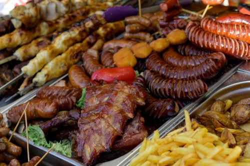 Preview: Grilled sausage with the addition of herbs and vegetables on the grill plate