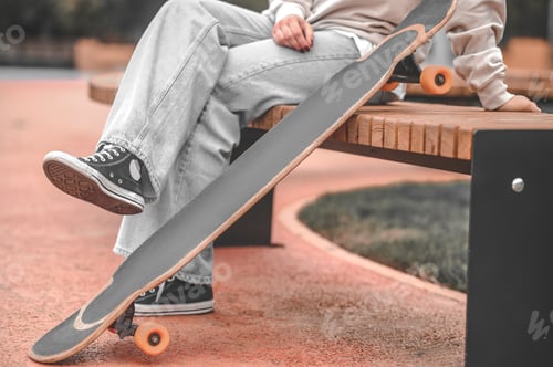 Preview: Legs near skateboard of person sitting in park