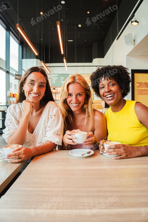 Preview: Vertical Group of young women drinking a coffee cup on a bar or restaurant. Three multiracial girls