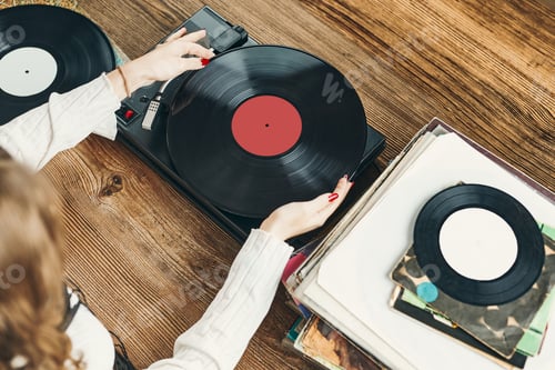 Preview: Young woman listening to music from vinyl record. Playing music on turntable player. Retro vintage