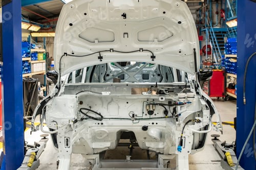 Preview: New car with open hood at a factory