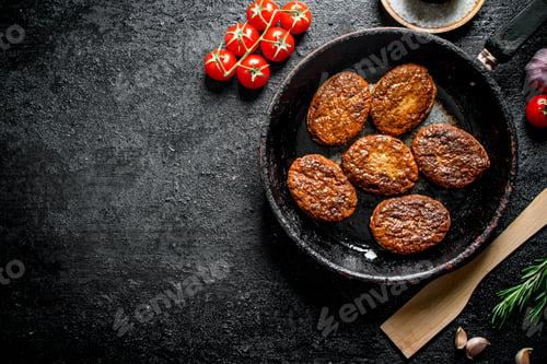 Preview: Cutlets in the pan with a wooden spatula and cherry.