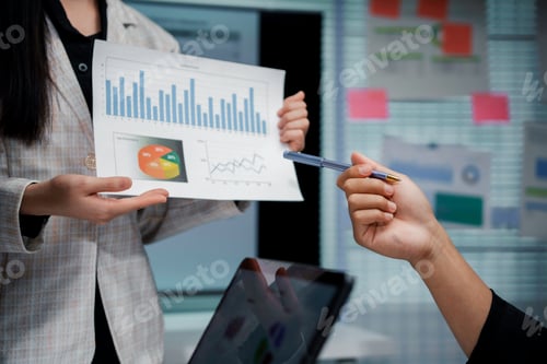 Preview: Businesswoman showing infographic charts and analyzing statistics with colleagues in meeting room
